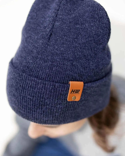 Denim blue knit beanie with folded cuff and tan leather-look logo patch