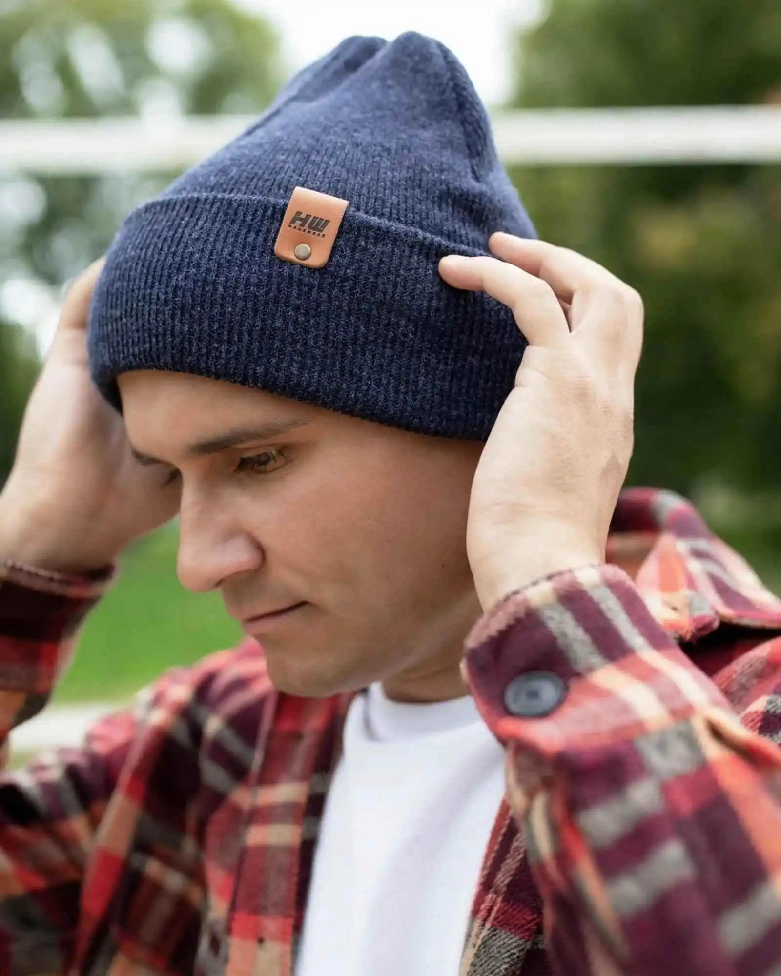 Denim blue knit beanie with folded cuff and tan logo patch on side