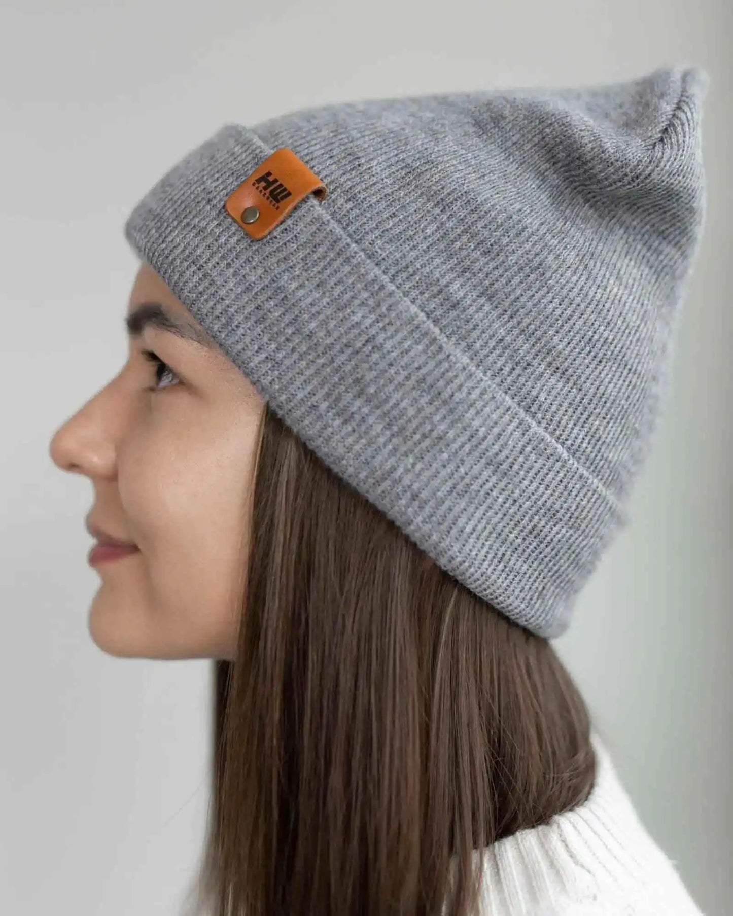 Koala gray knit beanie with folded cuff and brown leather logo patch, side view.