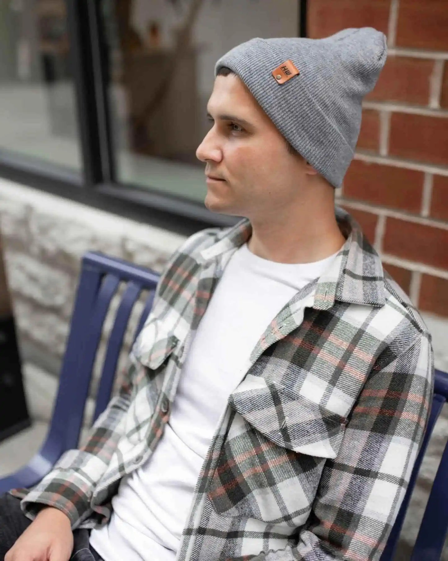 Gray knit beanie on person, angled side view with folded cuff and brown logo patch