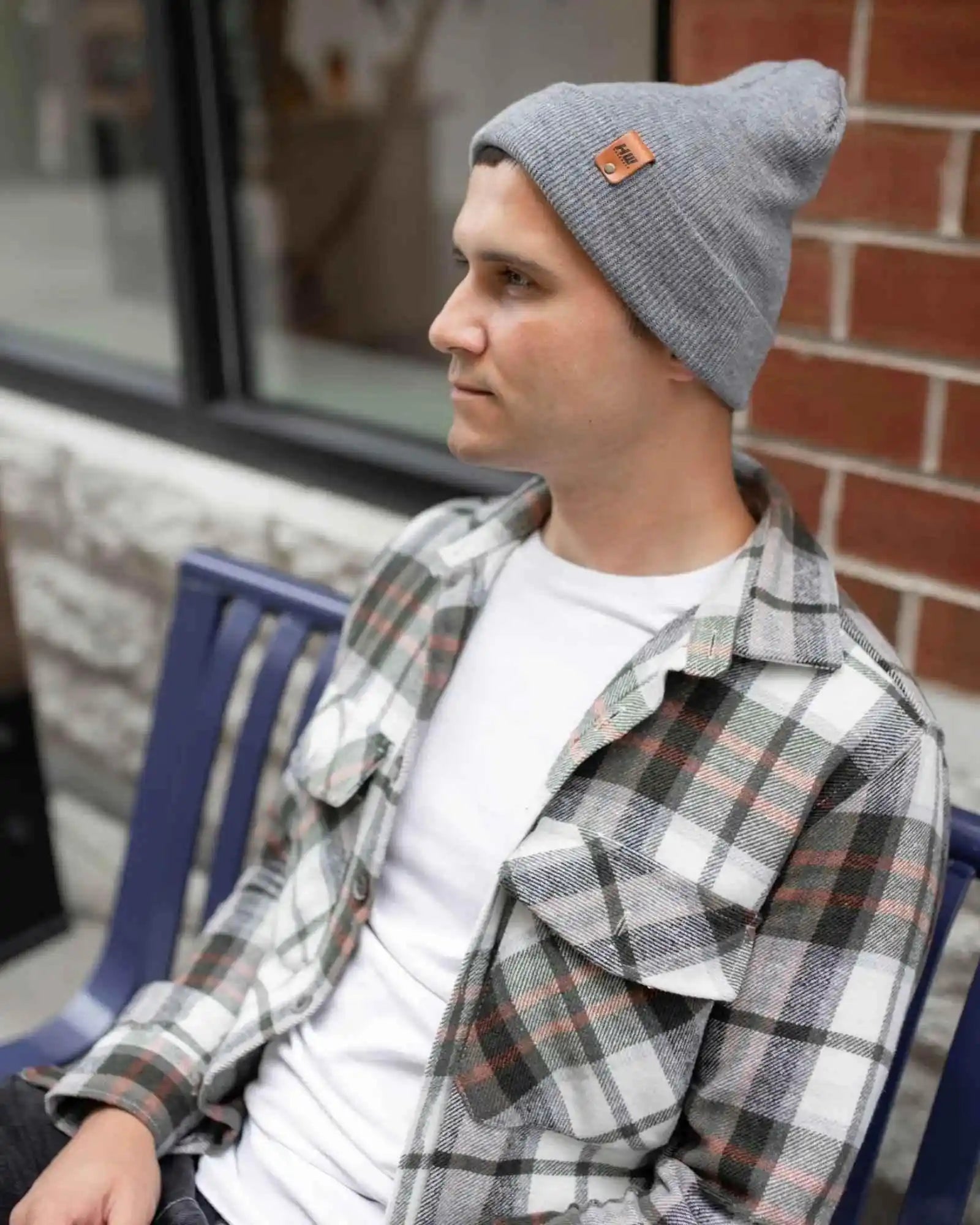 Gray knit beanie on person, angled side view with folded cuff and brown logo patch