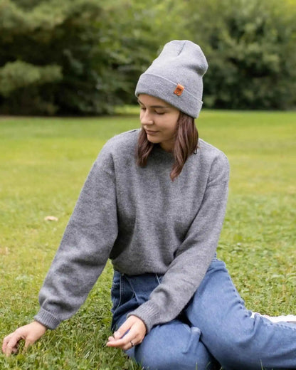 Gray knit beanie on person, folded cuff with brown logo patch