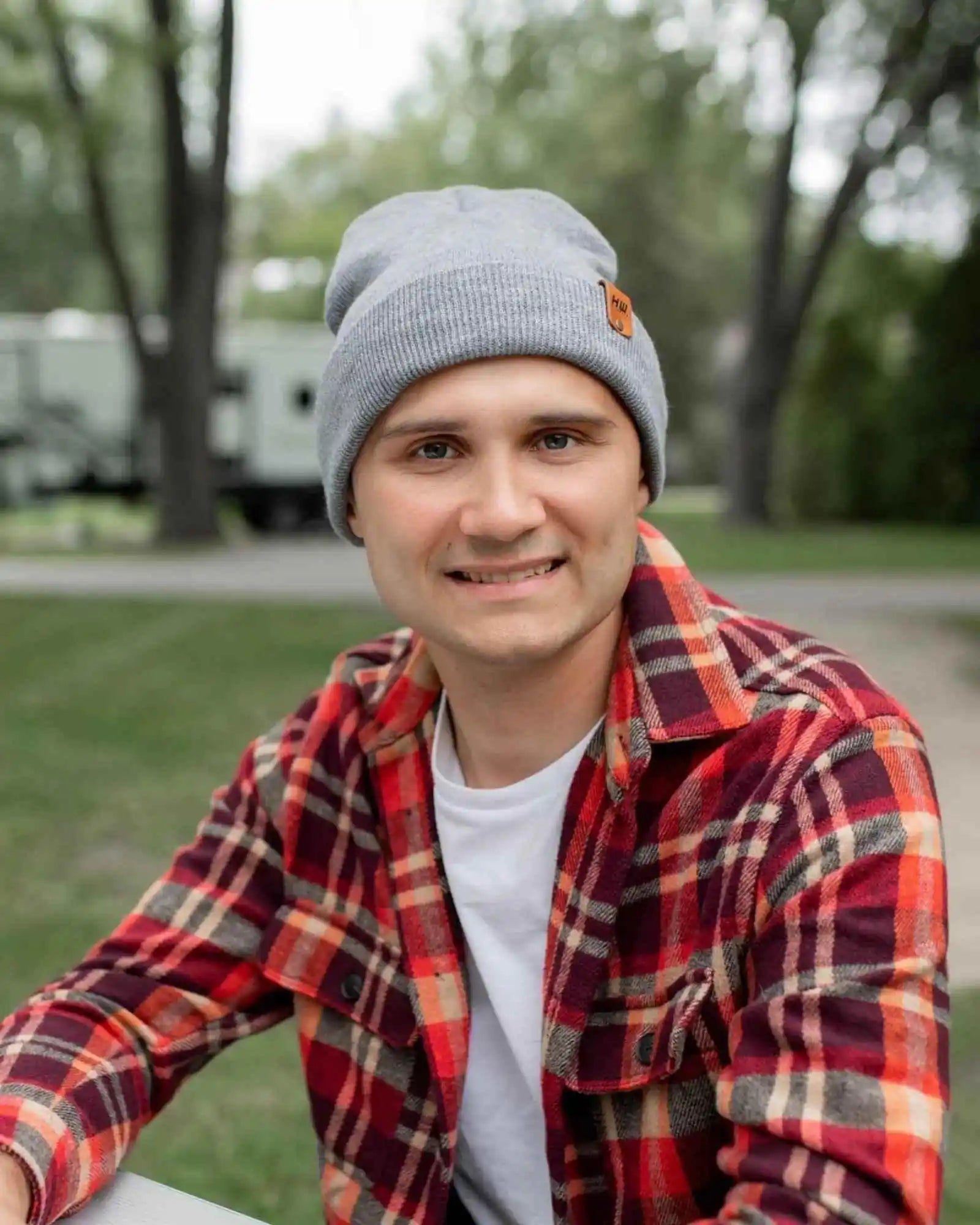 Gray knit beanie on person, front view with folded cuff and brown logo patch