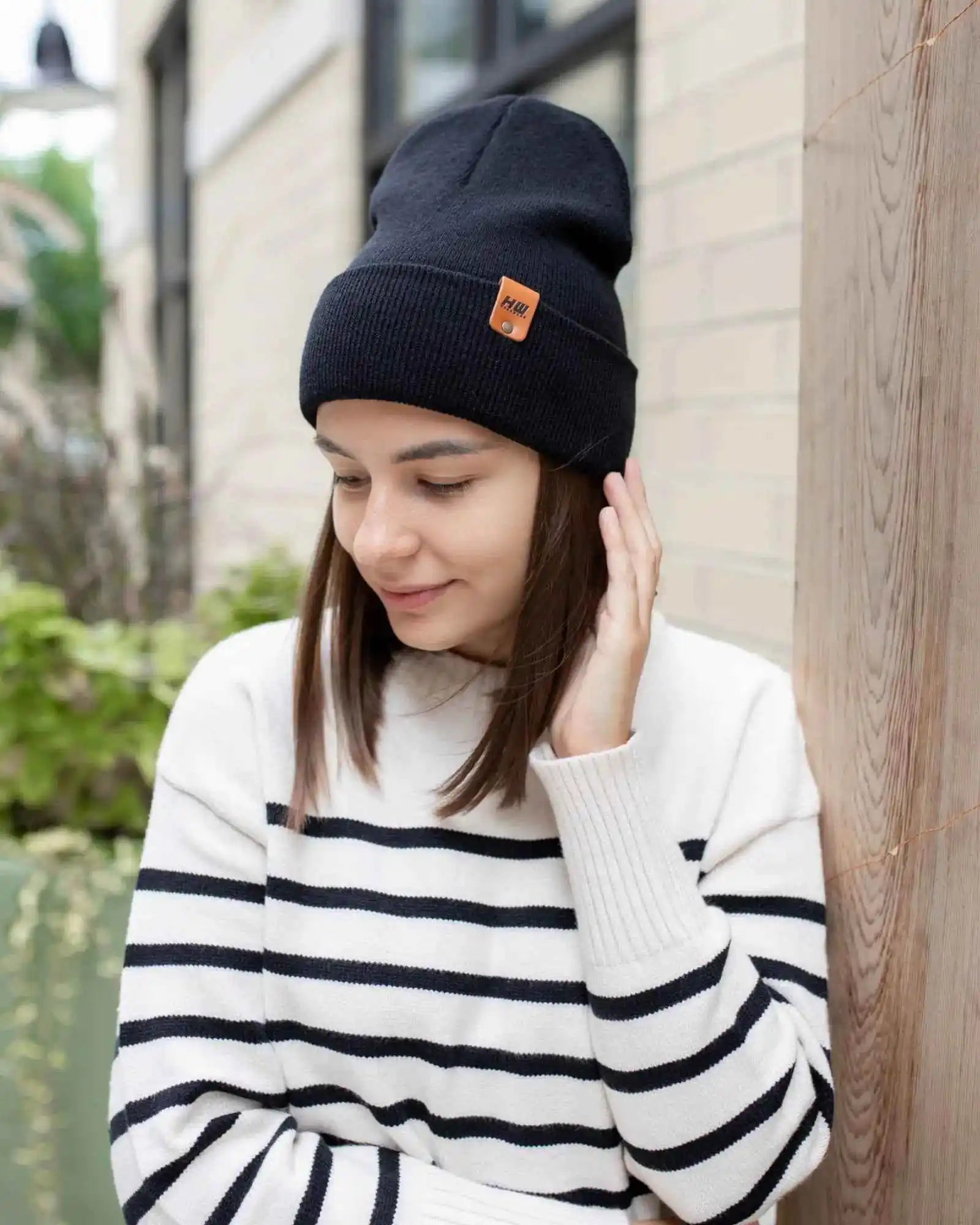 Dark cuff beanie with fold-over brim and orange logo patch, worn by woman