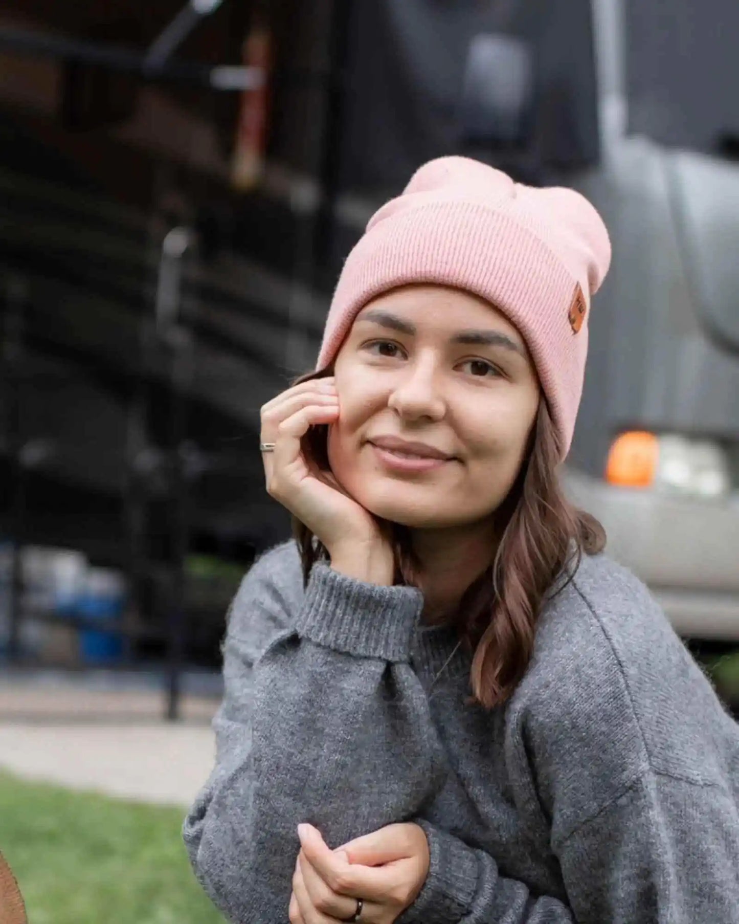 Pearl pink ribbed beanie with small logo patch, worn on head.
