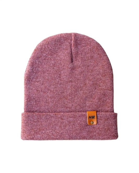 Rusty burgundy knit beanie with folded cuff and small tan brand patch logo.