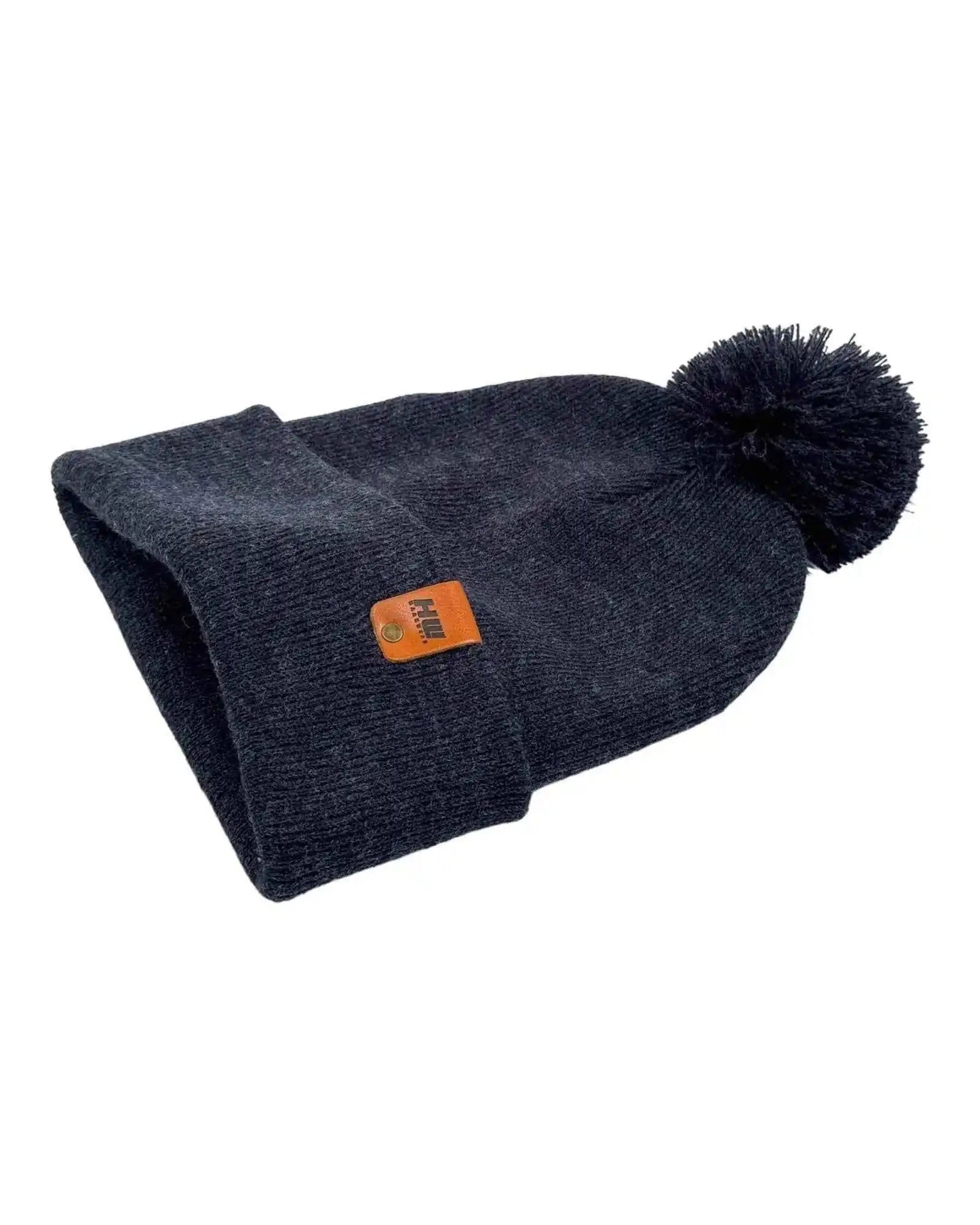 Denim blue knit beanie with folded cuff and pom pom, small orange label patch