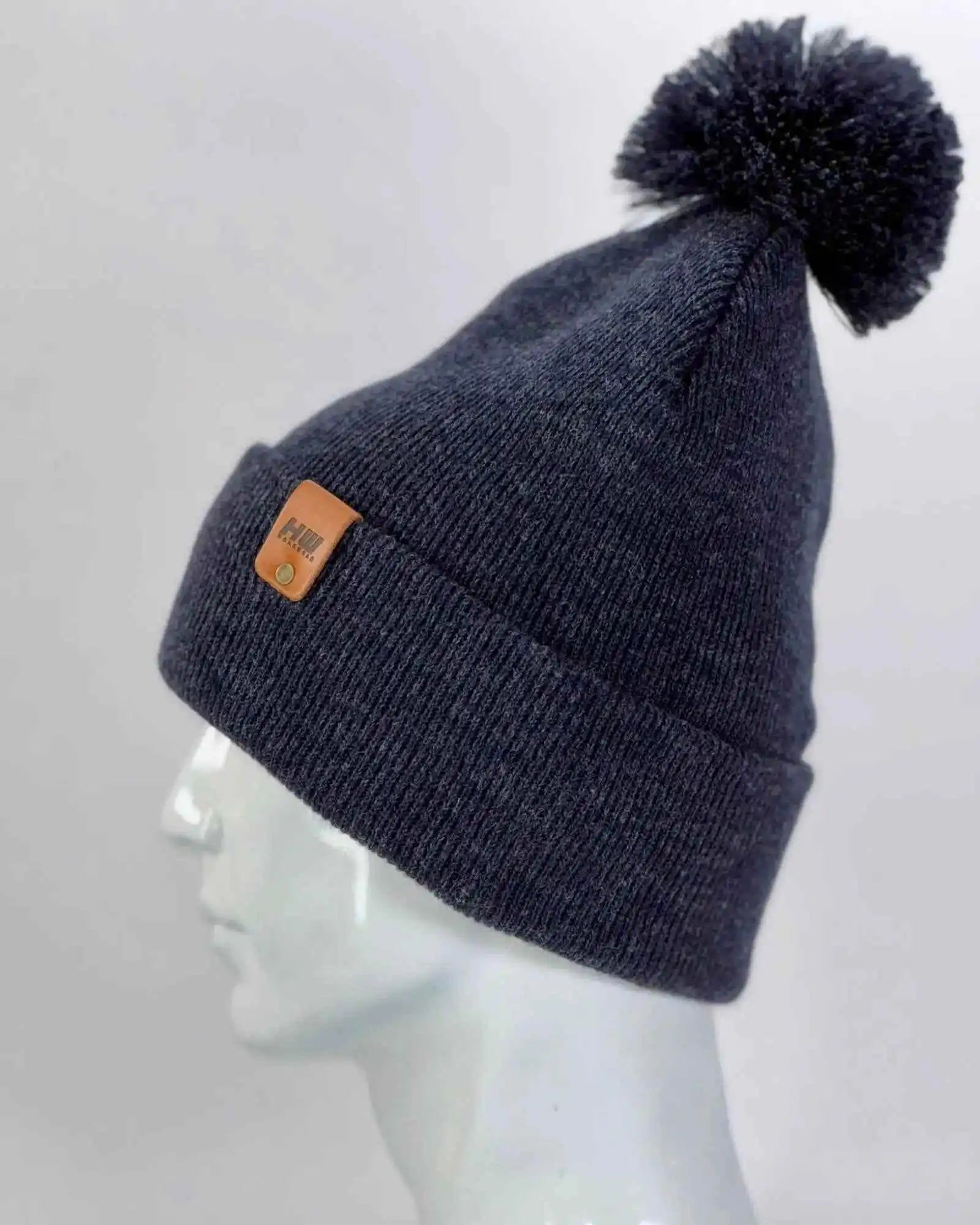 Denim blue knit beanie with folded cuff, pom pom top, orange patch on side