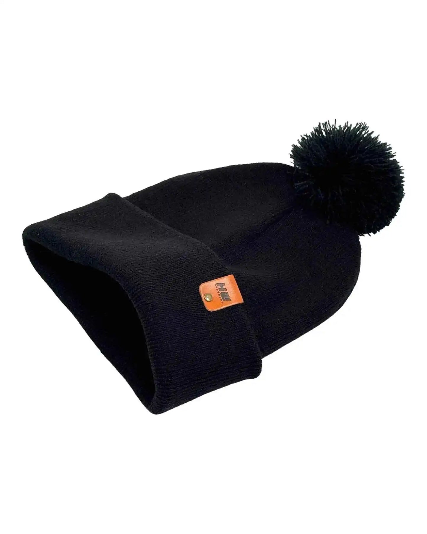 Folded midnight black knit beanie with pom pom and orange logo patch