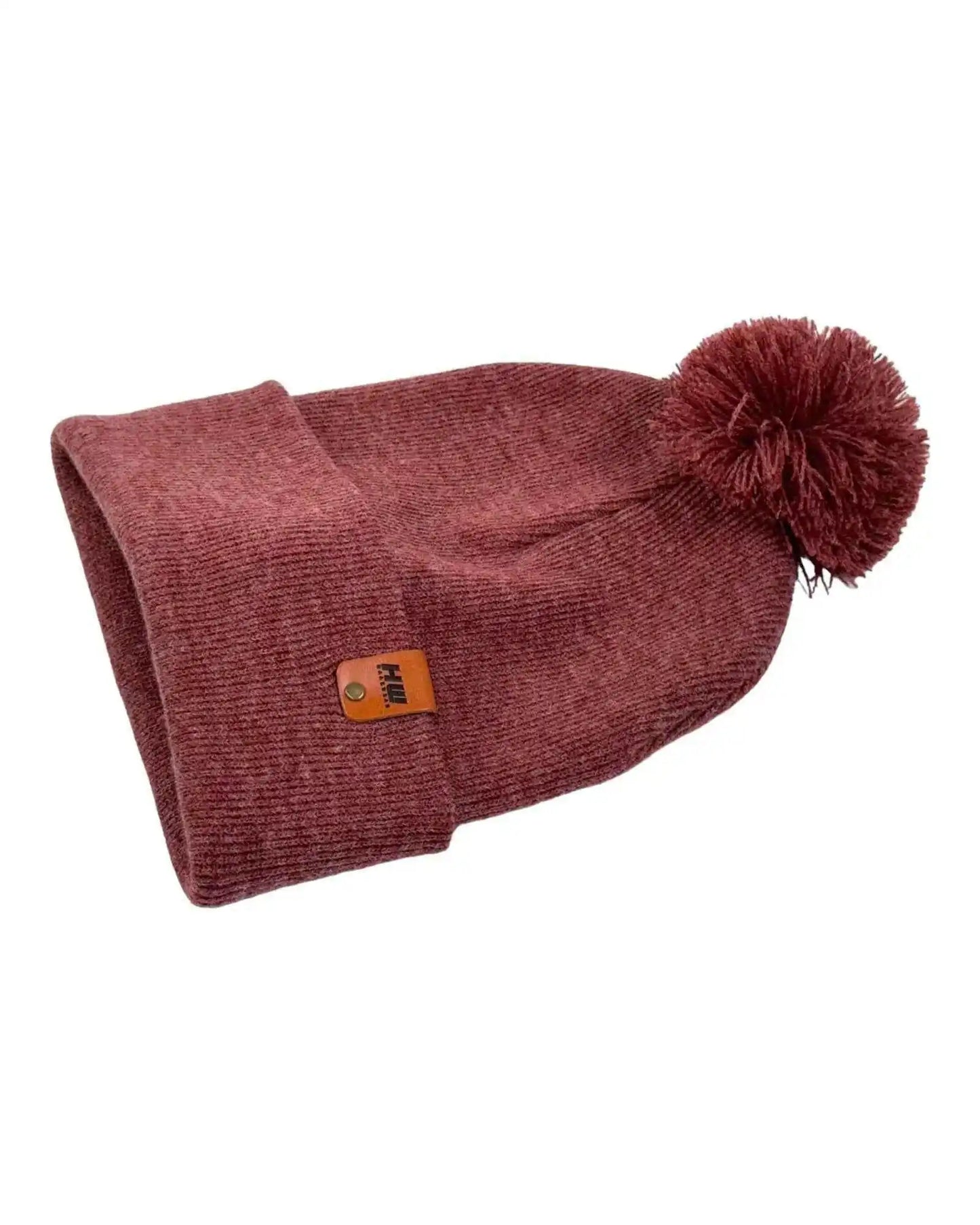 Rusty burgundy knit beanie with turned-up cuff, side logo patch, and pom pom