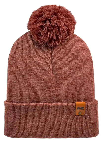 Rusty burgundy knit beanie with folded cuff, large pom pom, and logo patch