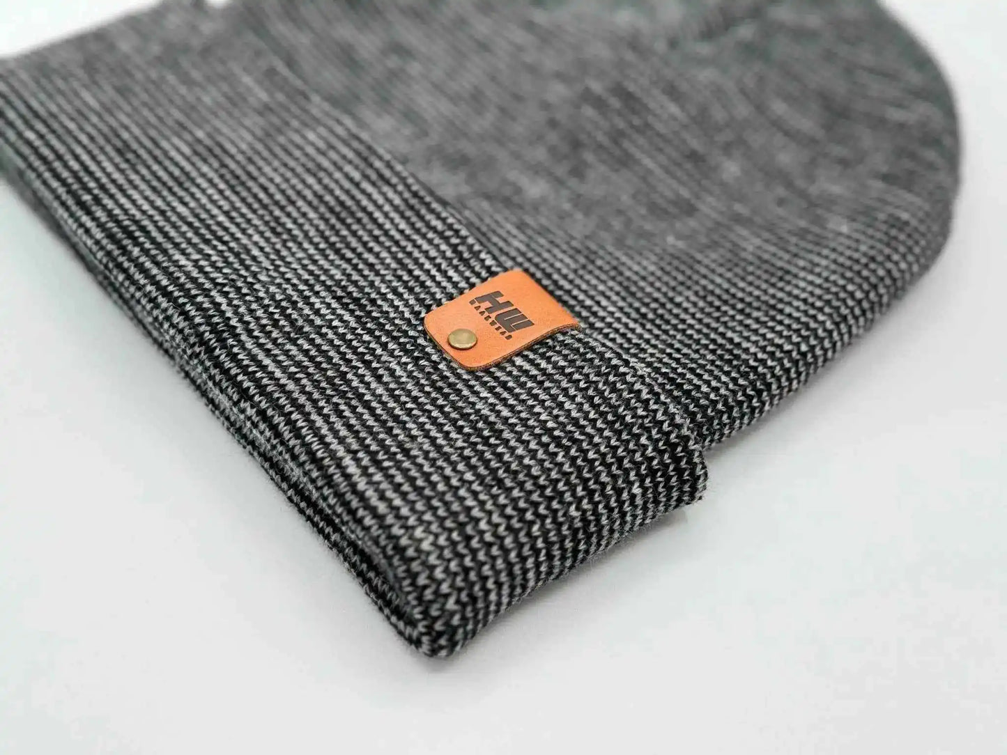 Cuffed beanie corner close-up with orange logo patch on dark gray knit