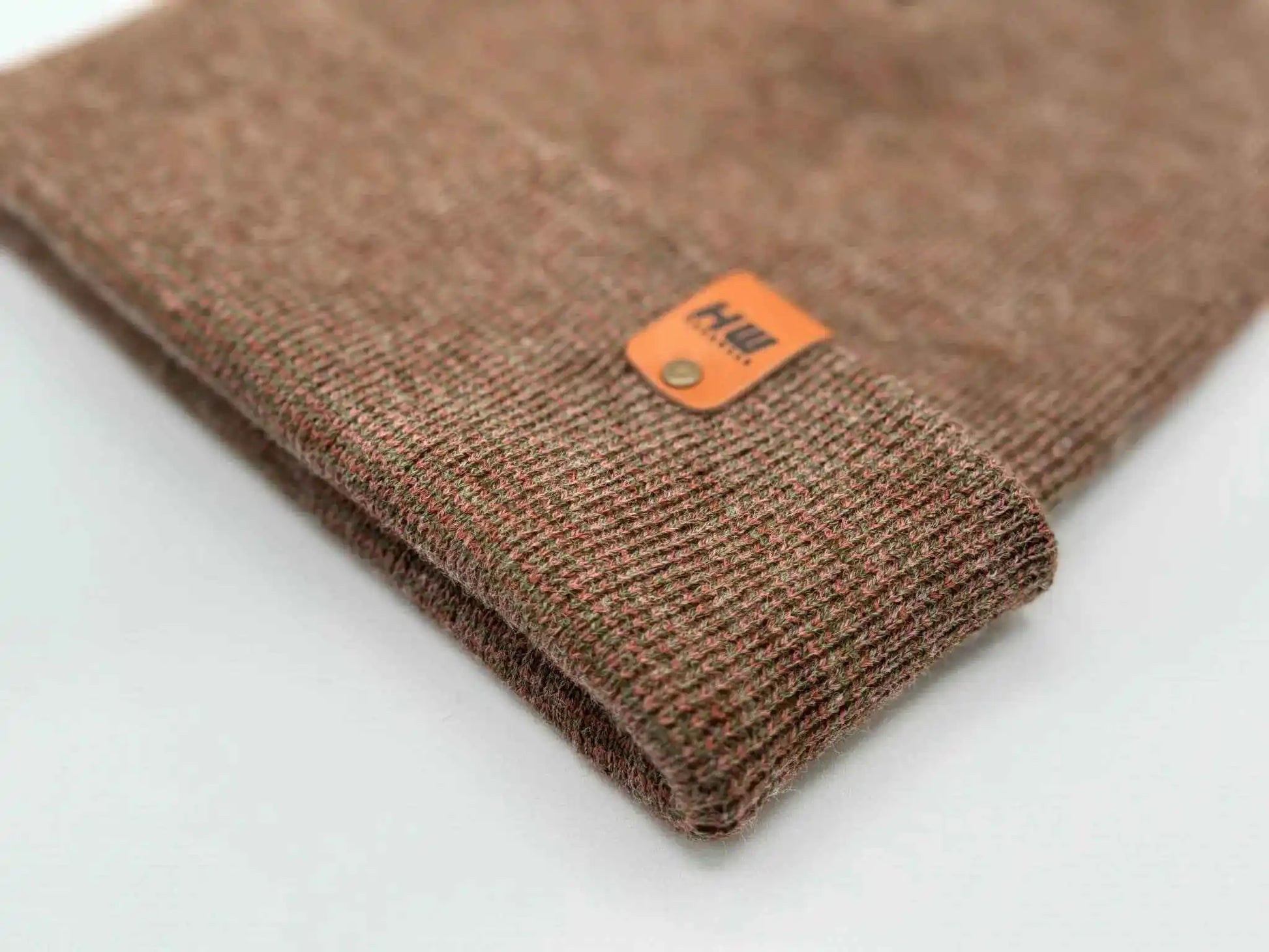 Brown knit beanie cuff with small orange woven logo patch