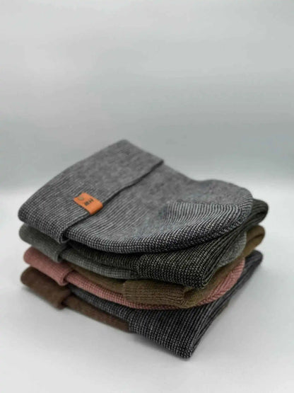 Stack of folded knit beanies in gray, dark gray, and brown with orange patches
