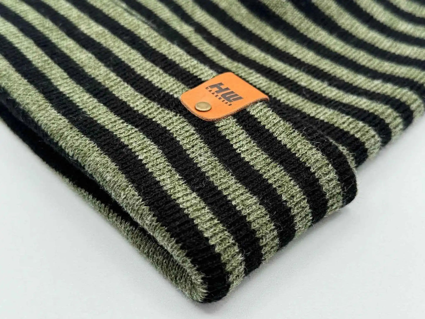 Cuffed knit beanie detail: black and green stripes with orange logo patch