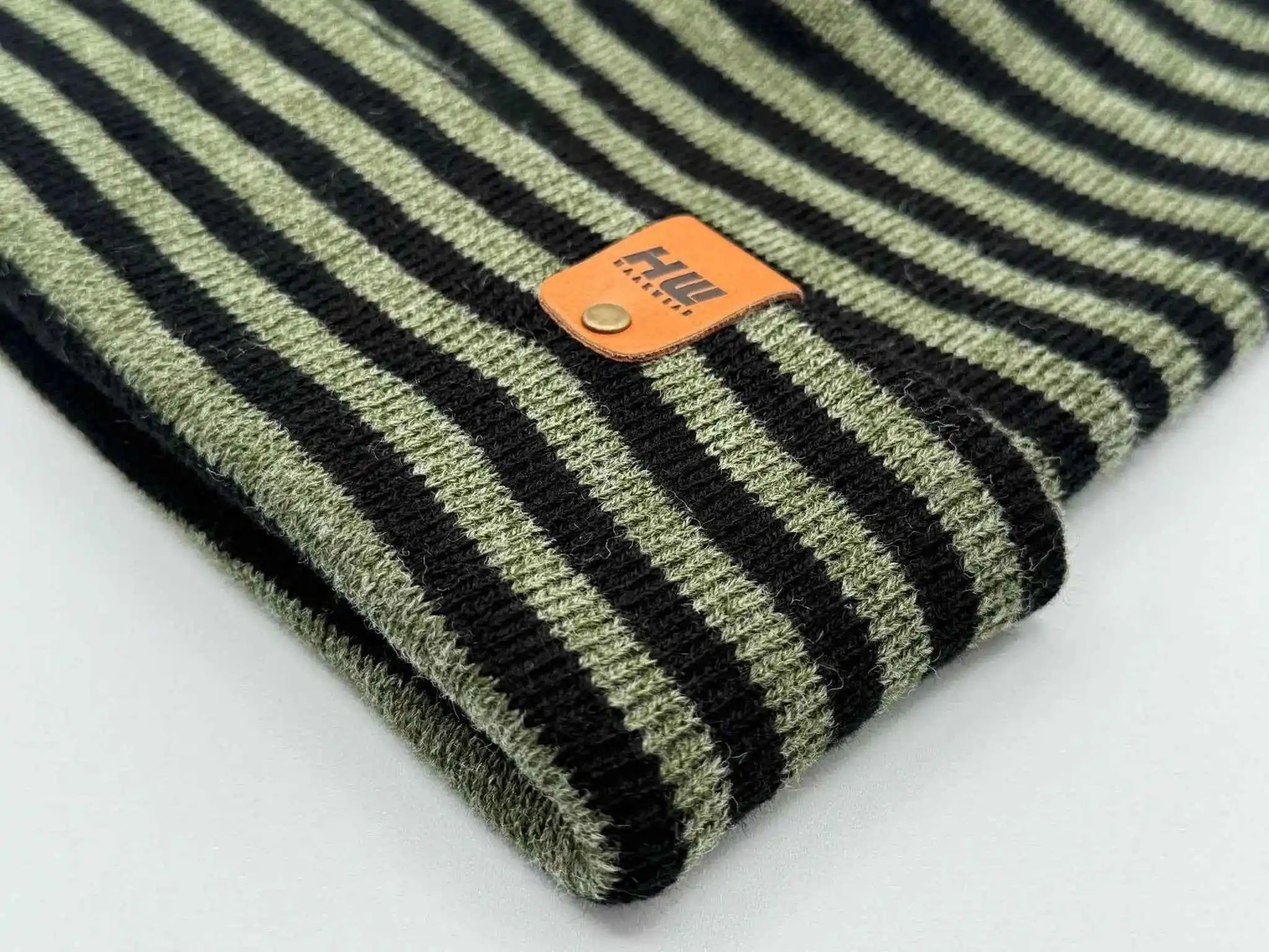 Cuffed knit beanie detail: black and green stripes with orange logo patch