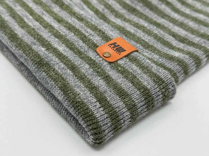 Gray and green striped ribbed beanie close-up with orange brand patch on cuff