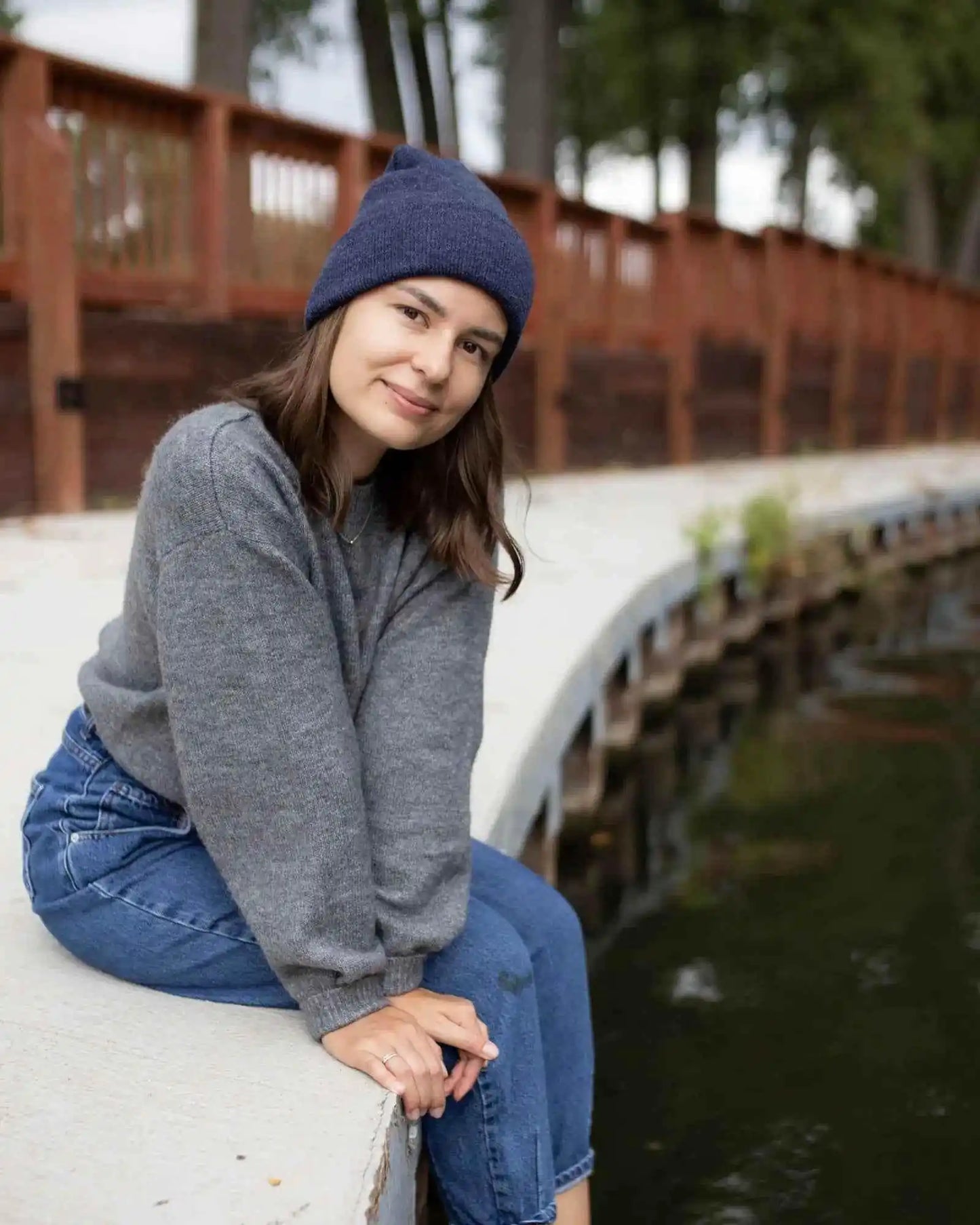 Denim blue knit beanie with folded cuff on person sitting