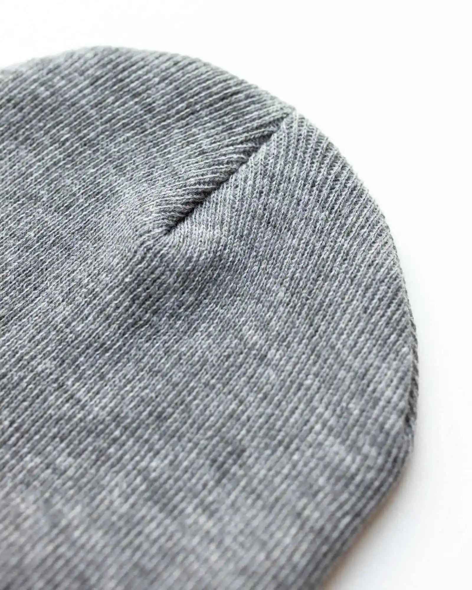 Gray knit beanie close-up with textured fabric and top seam
