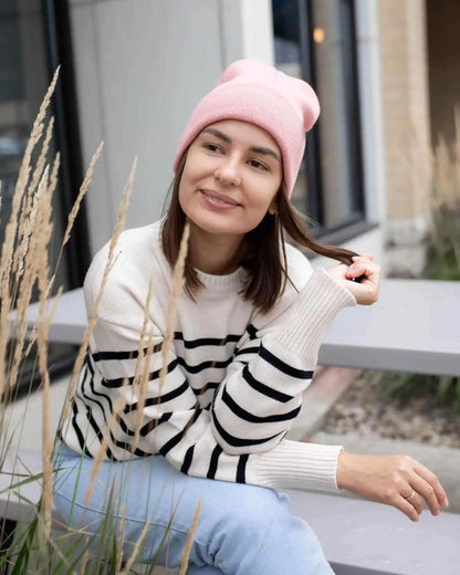 Pink ribbed knit beanie worn with folded cuff on a person