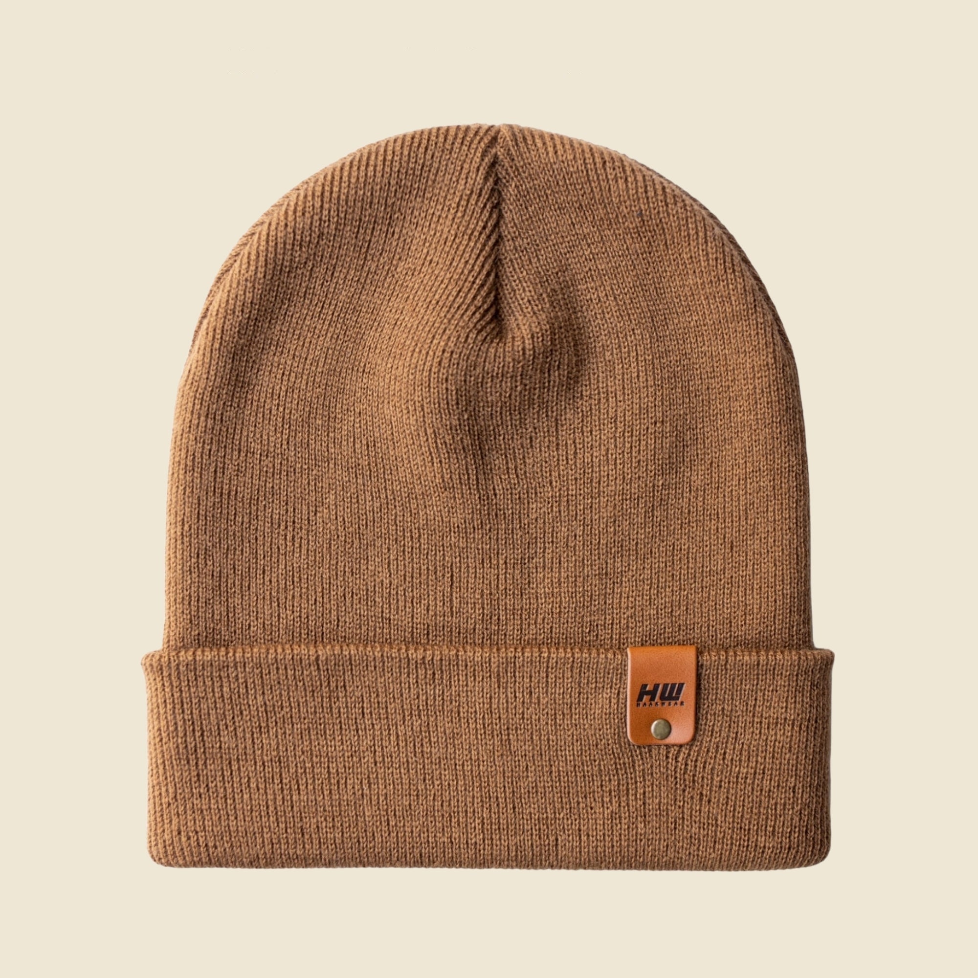 Brown beanie with a leather patch on a beige background