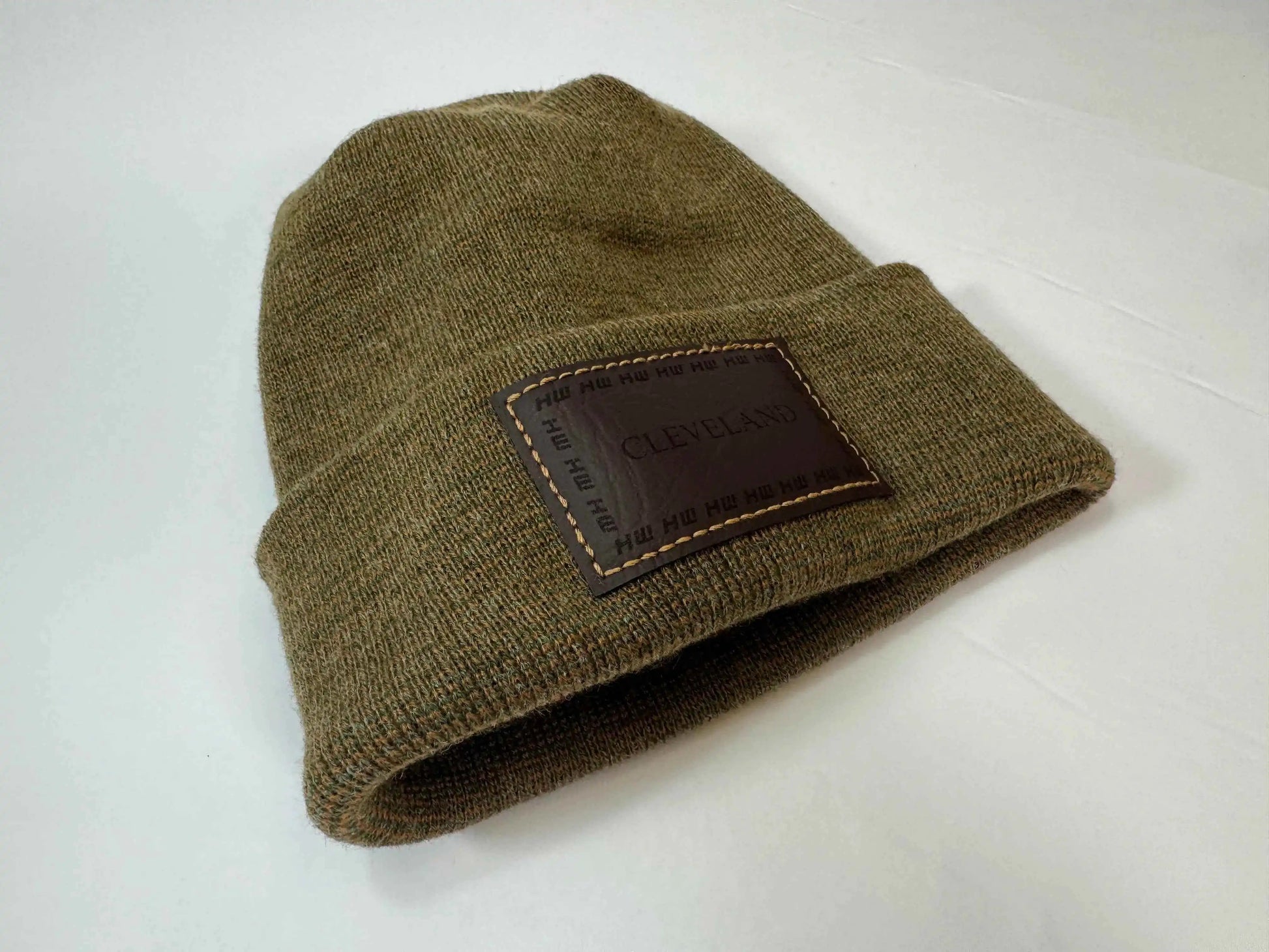 Brown knit beanie laid on side with folded cuff and Cleveland logo patch