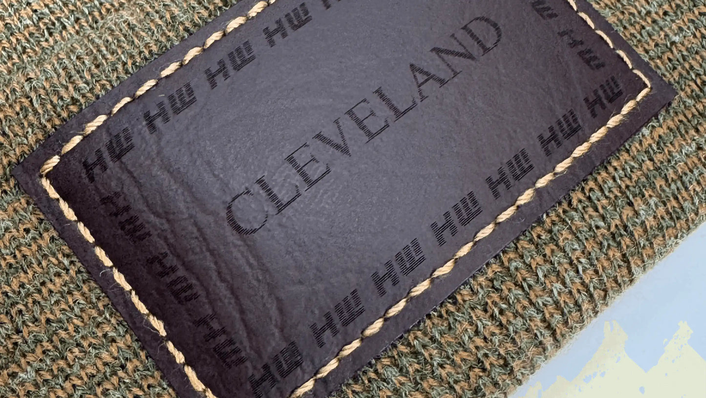 Brown and green knit beanie showing rectangular Cleveland label patch detail