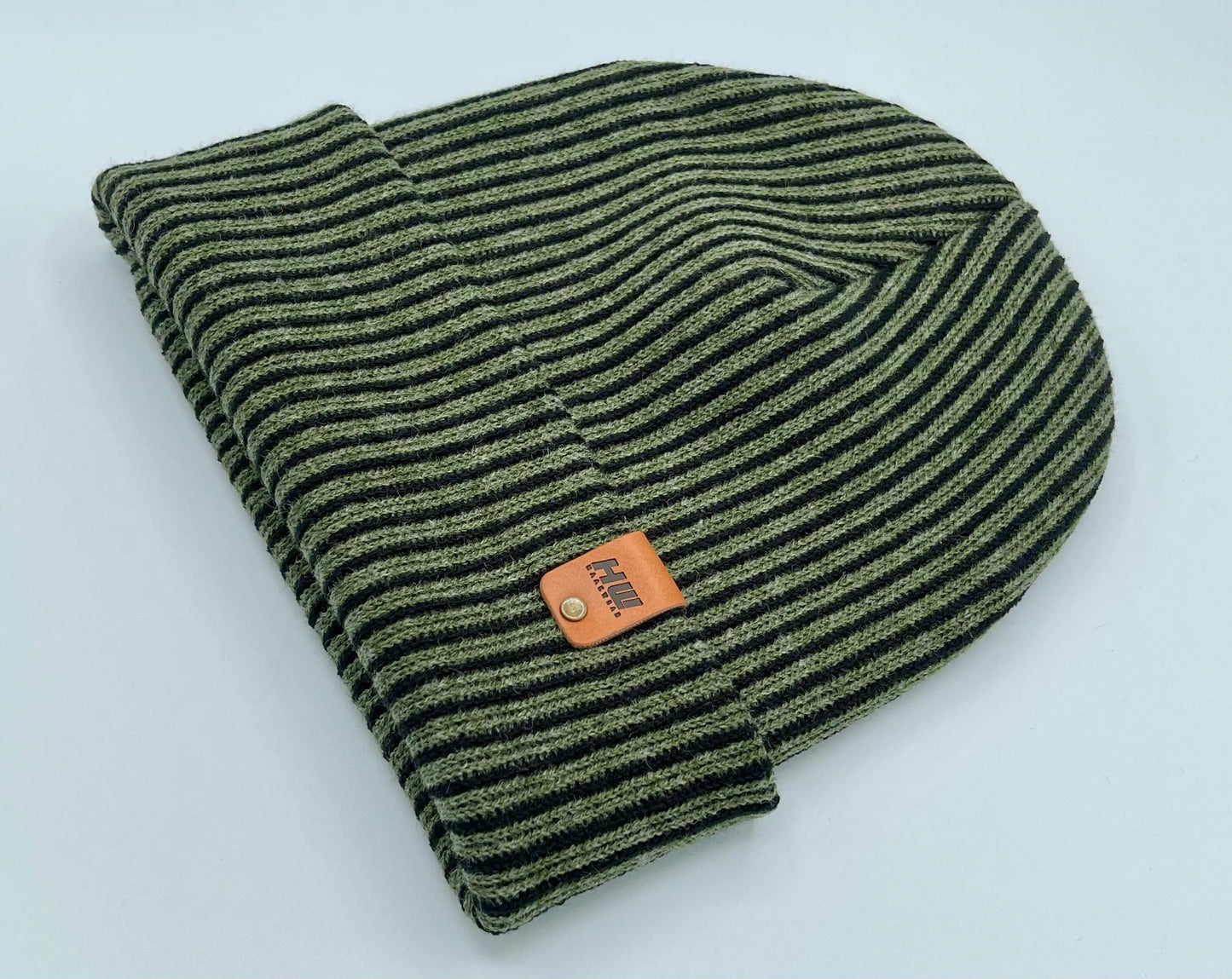 Folded green striped beanie with wide cuff and brown leather label at center