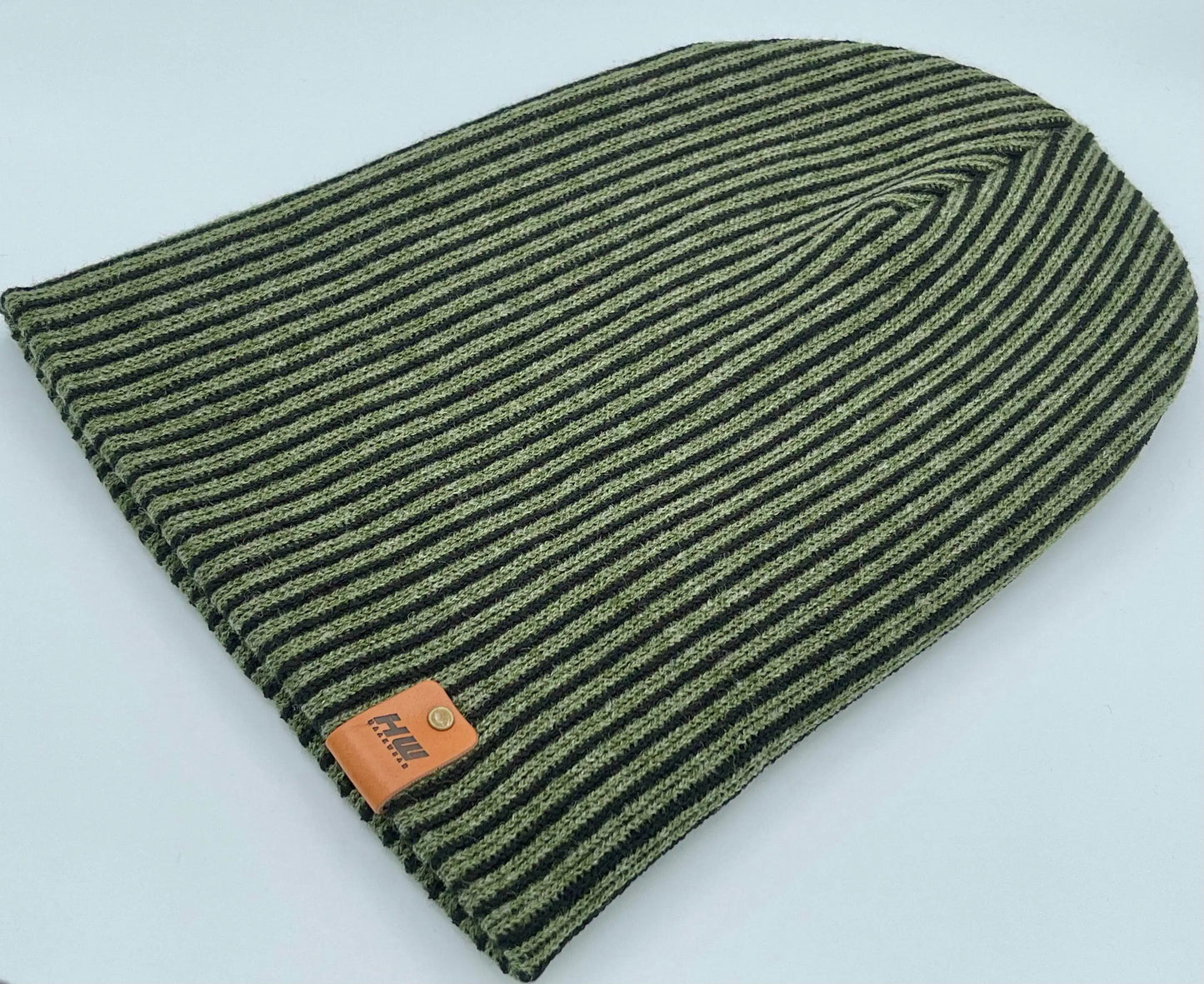 Green ribbed striped beanie with wide cuff and brown leather label near hem
