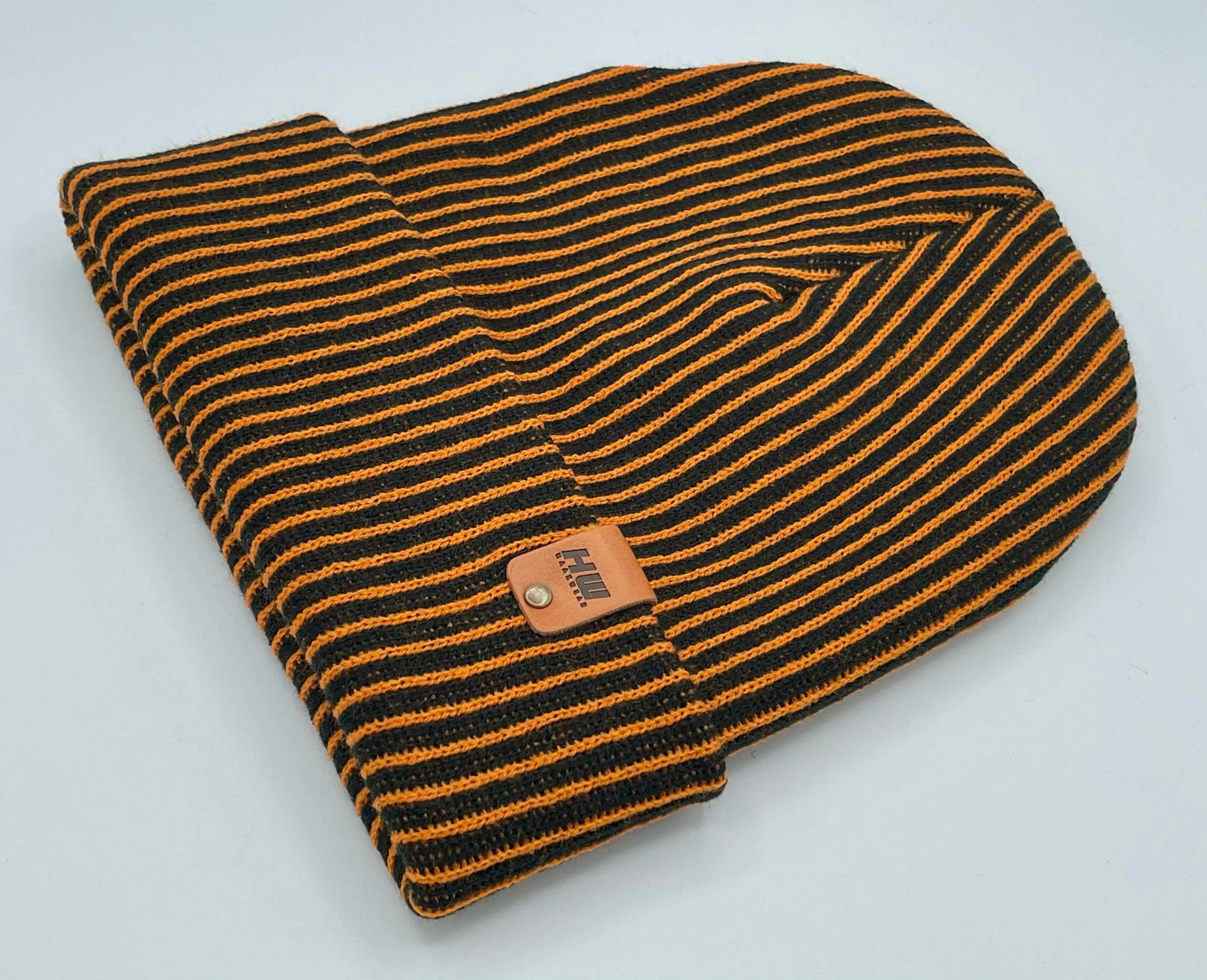 Folded black and orange striped beanie with ribbed cuff and woven patch
