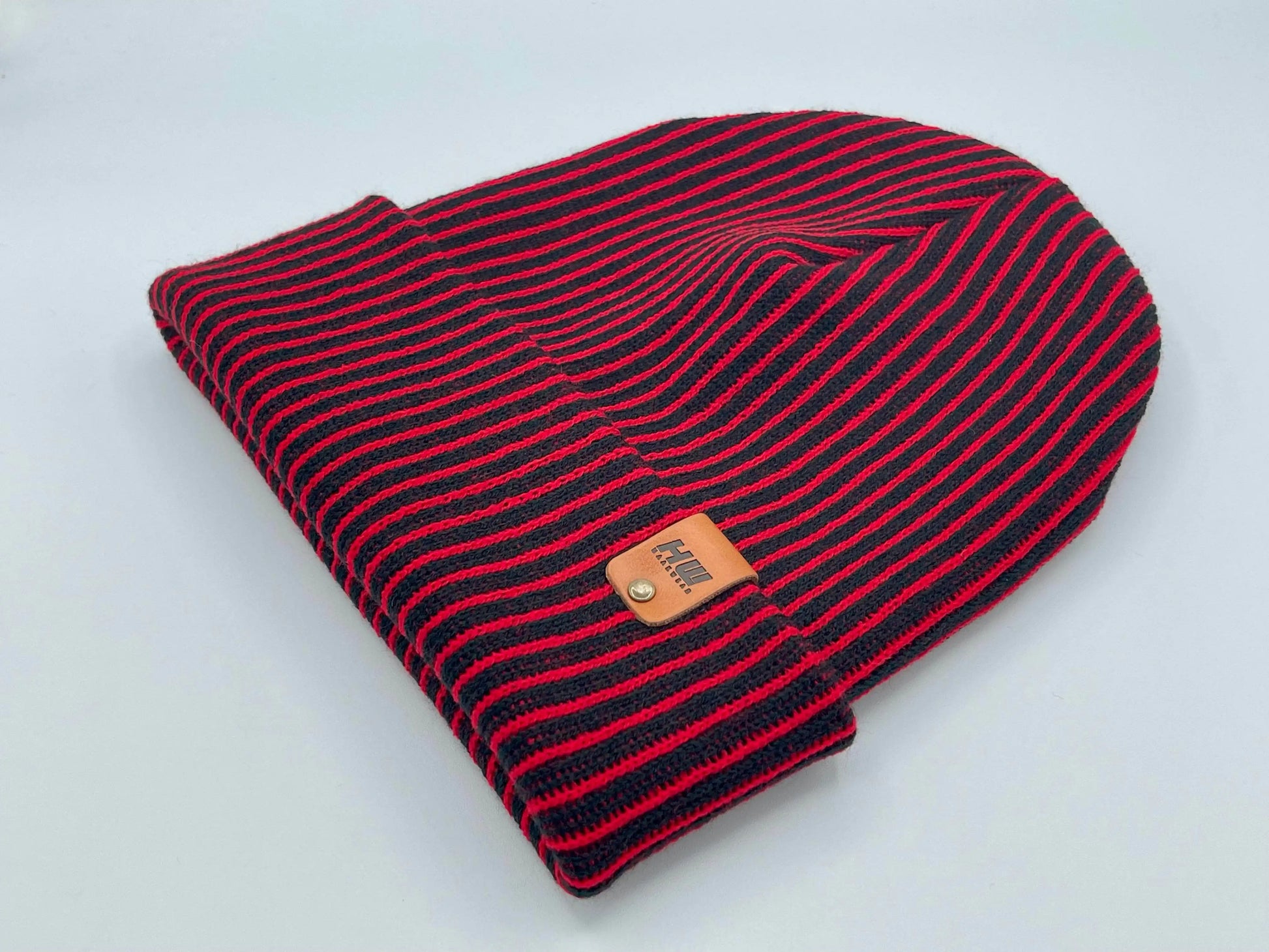 Folded beanie with wide ribbed red-and-black stripes and leather logo patch