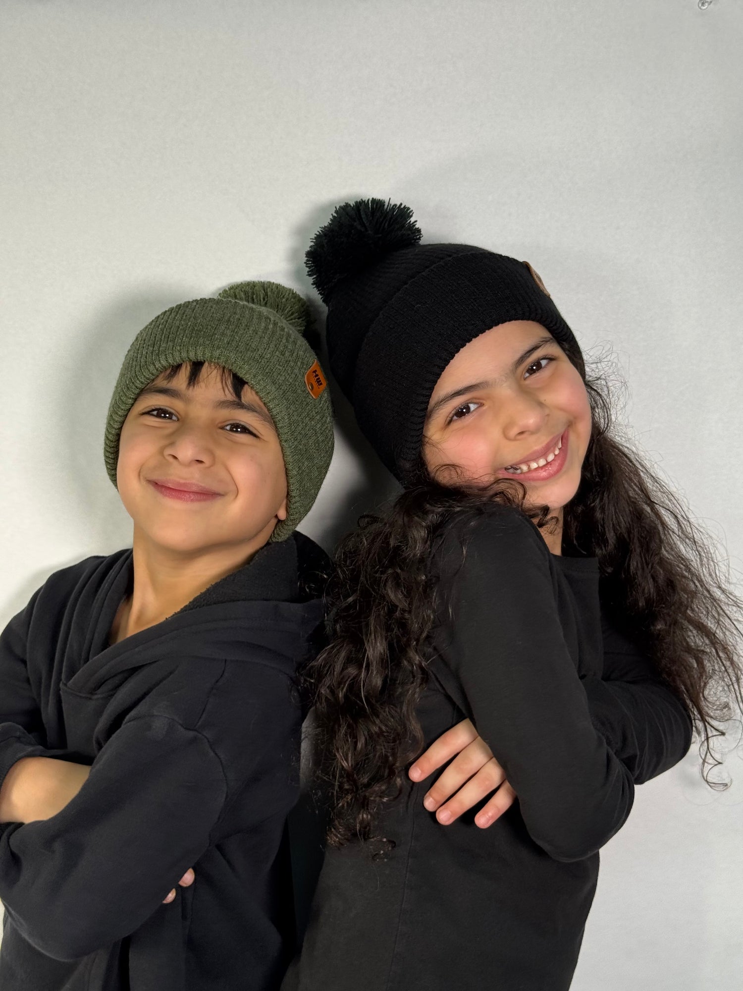 Two children wearing beanies and dark clothing against a plain background. Made in USA beanies by haakwear with free shipping USA only