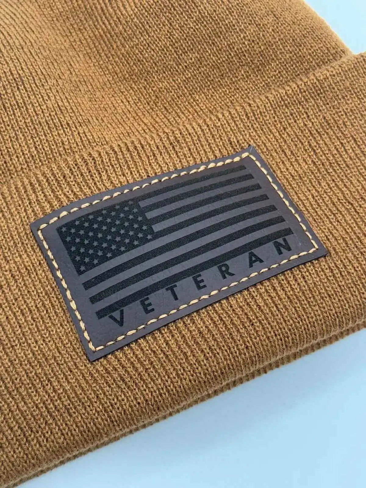 Tan knit cuffed beanie with rectangular Veteran flag patch.