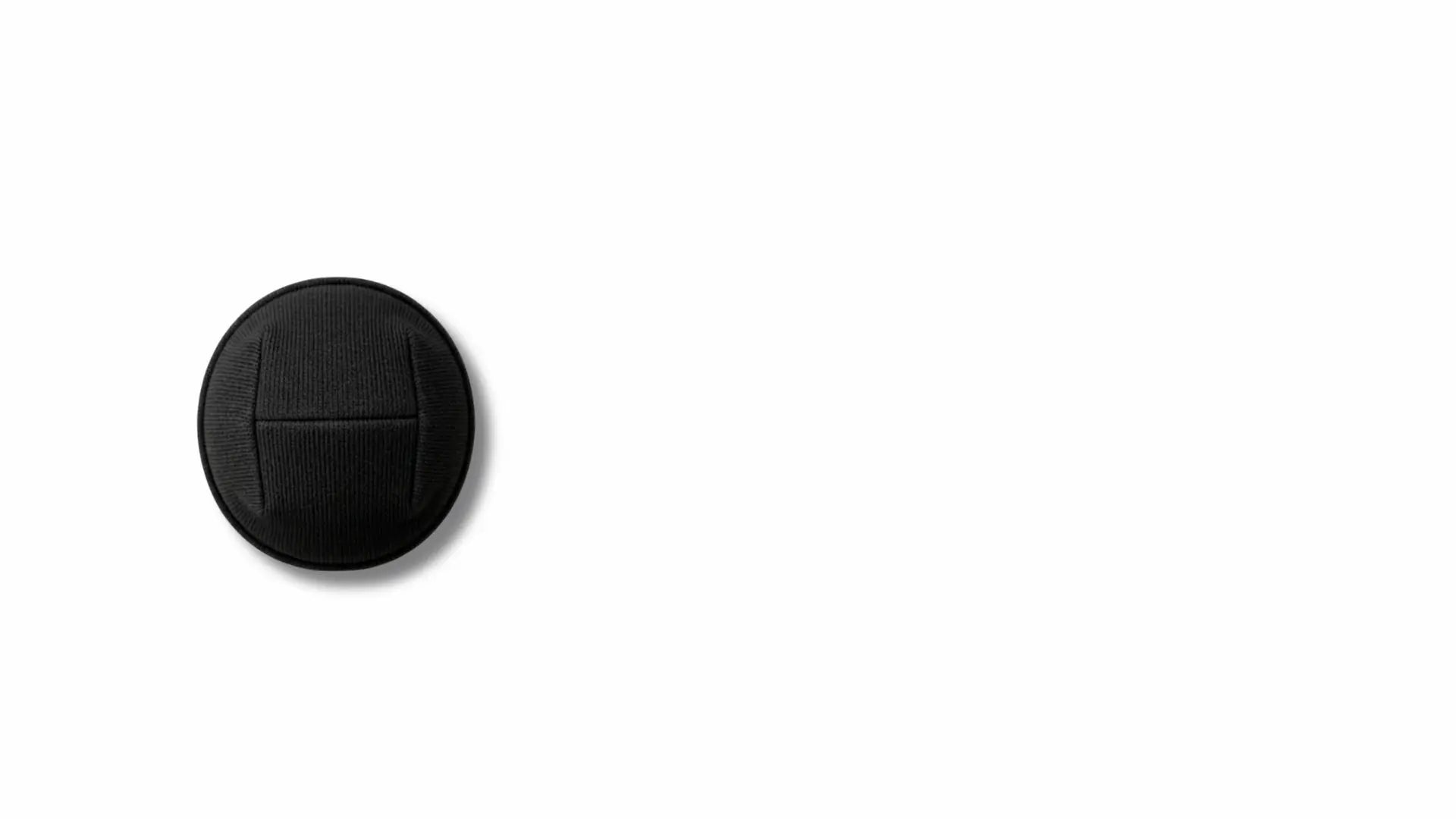 A single black circular button with a textured surface and a horizontal seam, shown on a plain white background.