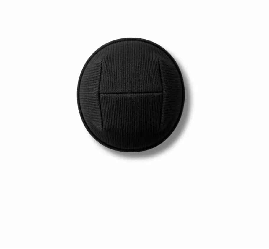 A single black circular button with a textured surface and a horizontal seam, shown on a plain white background.