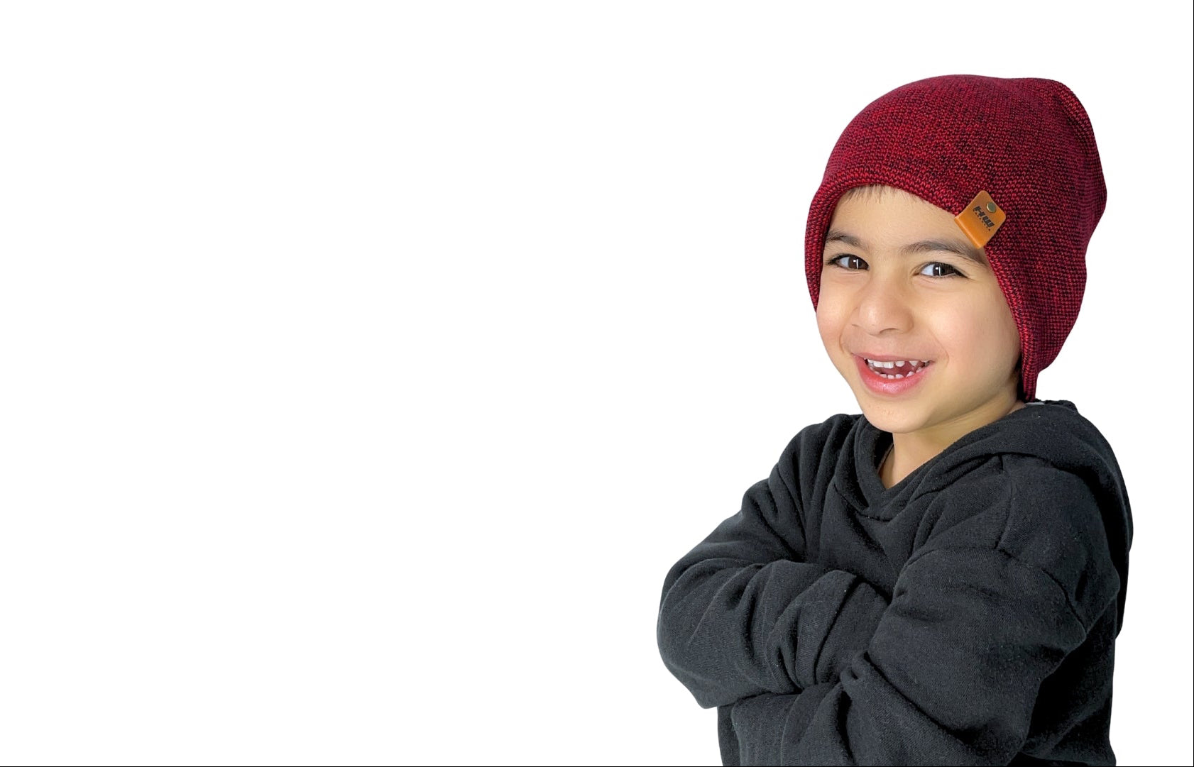 Child wearing a red knit hat with a brand tag on a white background