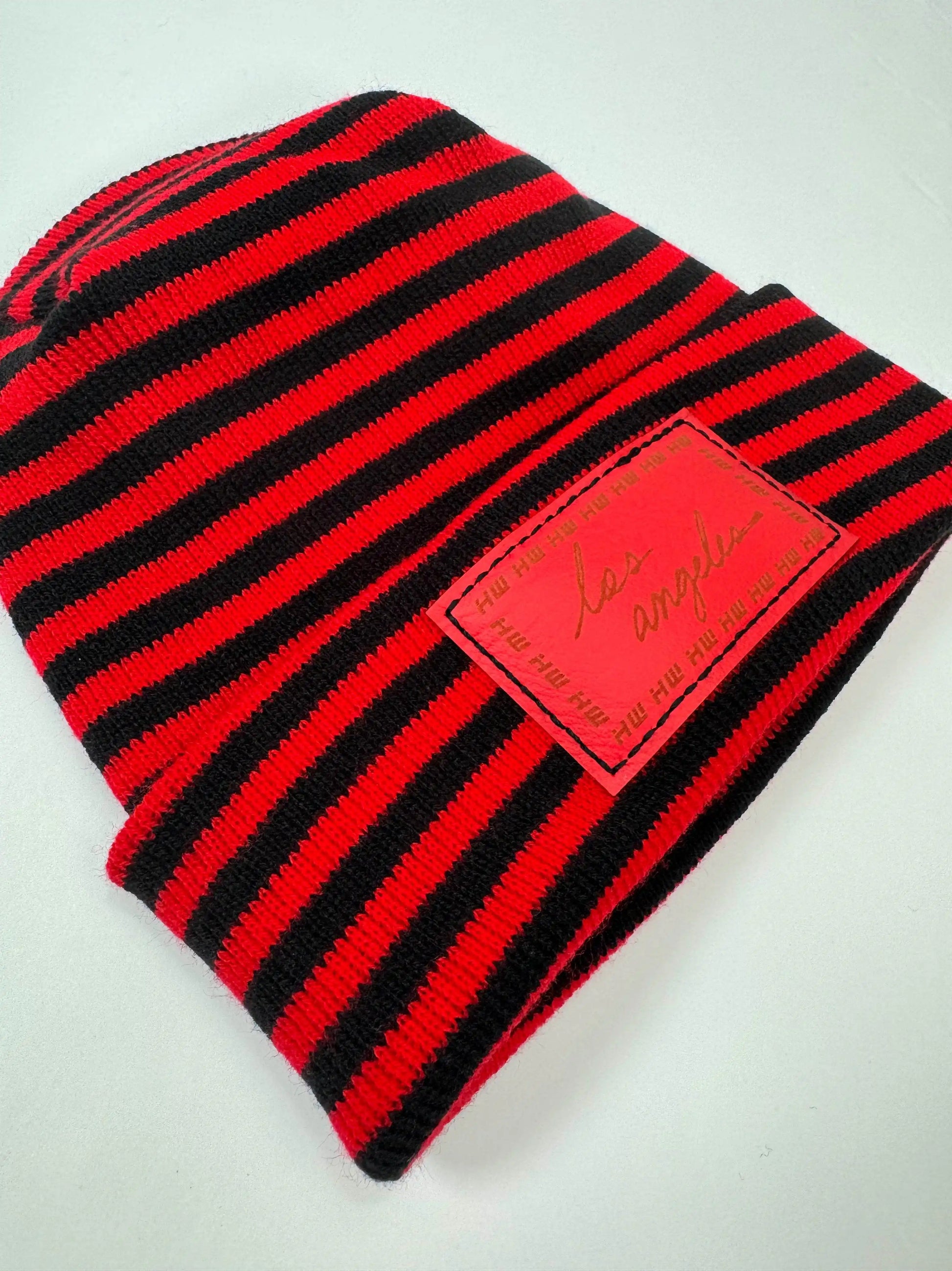 Striped black and red beanie with red logo patch on fold-up cuff
