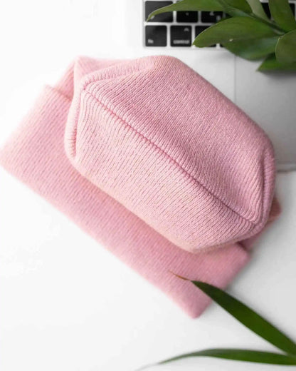 Light pink ribbed knit beanie with folded cuff, laid flat.