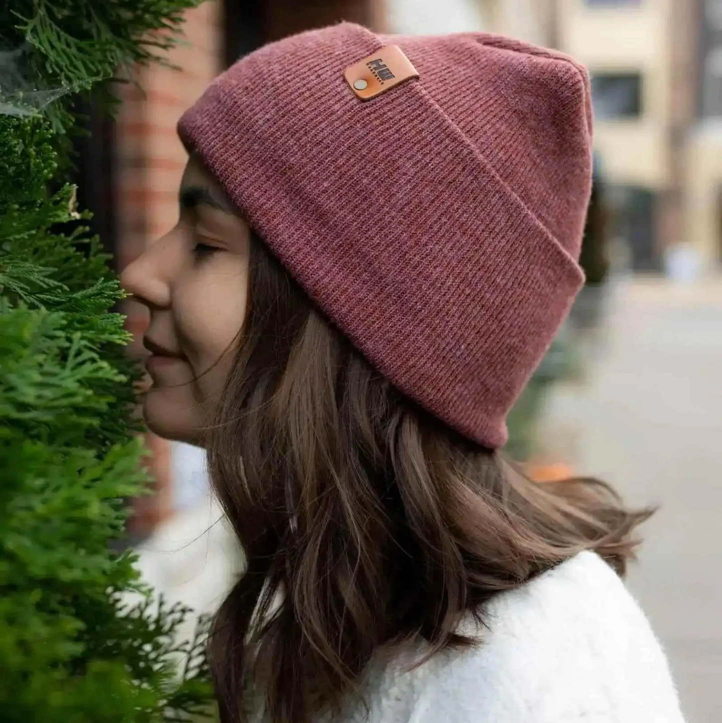 Mauve ribbed knit beanie with folded cuff and small brown logo patch.