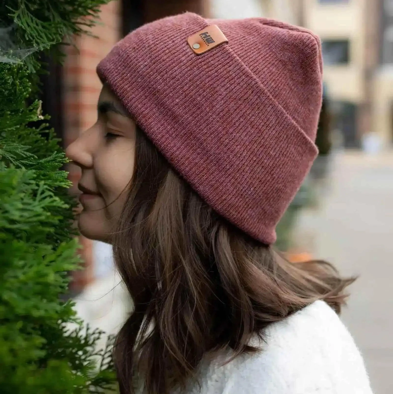 Mauve ribbed knit beanie with folded cuff and small brown logo patch.