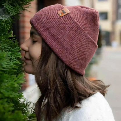 Mauve ribbed knit beanie with folded cuff and small brown logo patch.