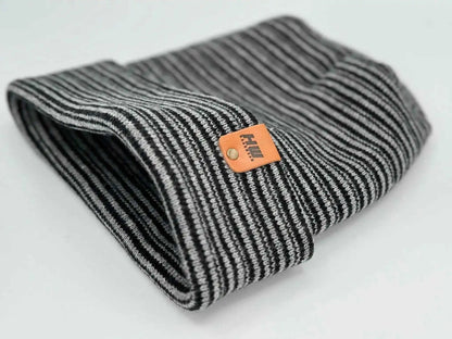 Folded black and gray striped knit beanie with orange logo tag