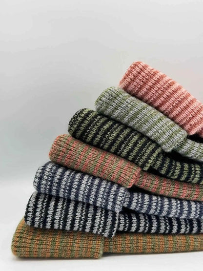 Stack of striped beanies with ribbed cuffs and orange logo patches, multicolor knit