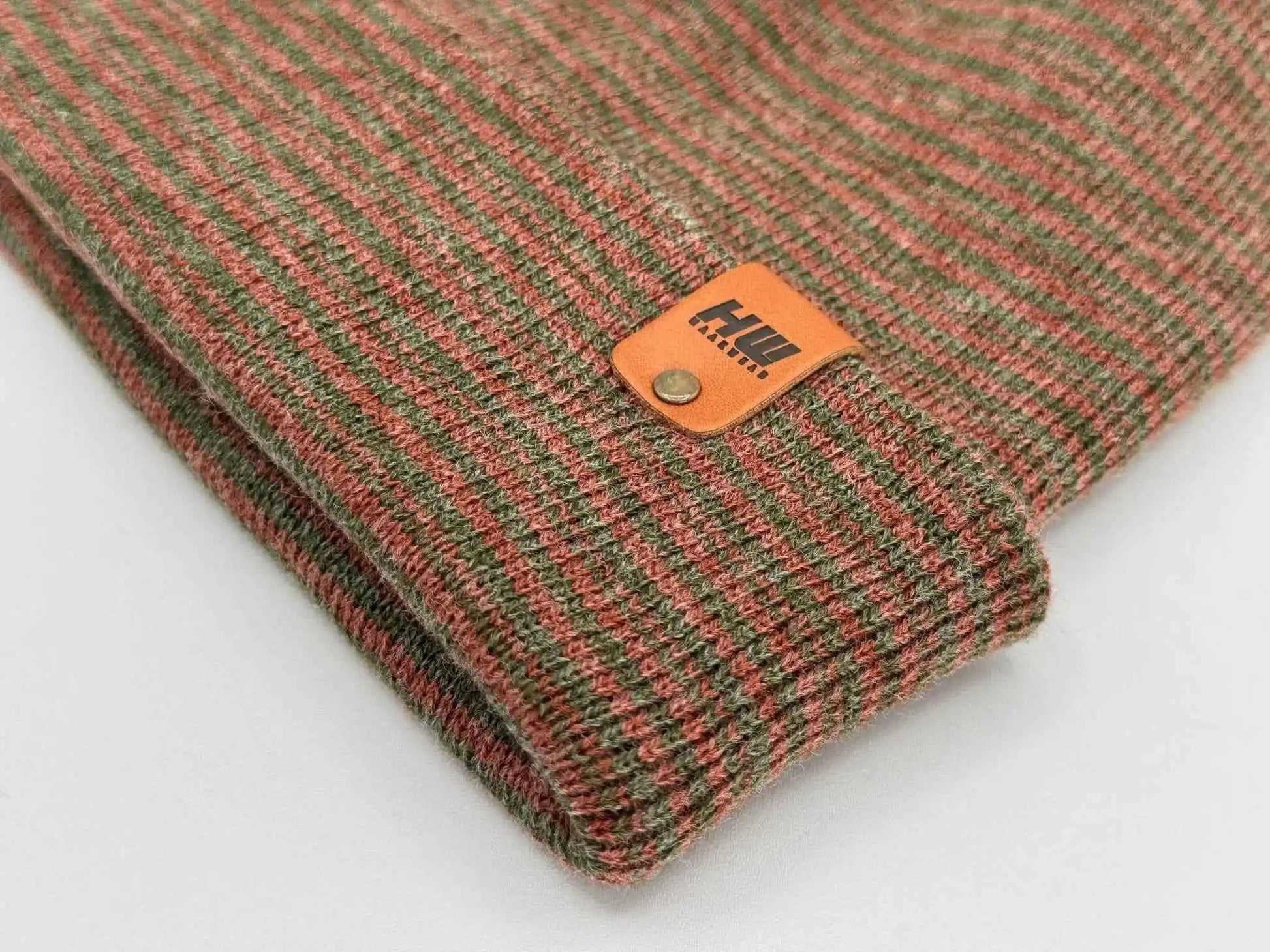 Ribbed knit beanie with burgundy and green stripe texture, logo patch