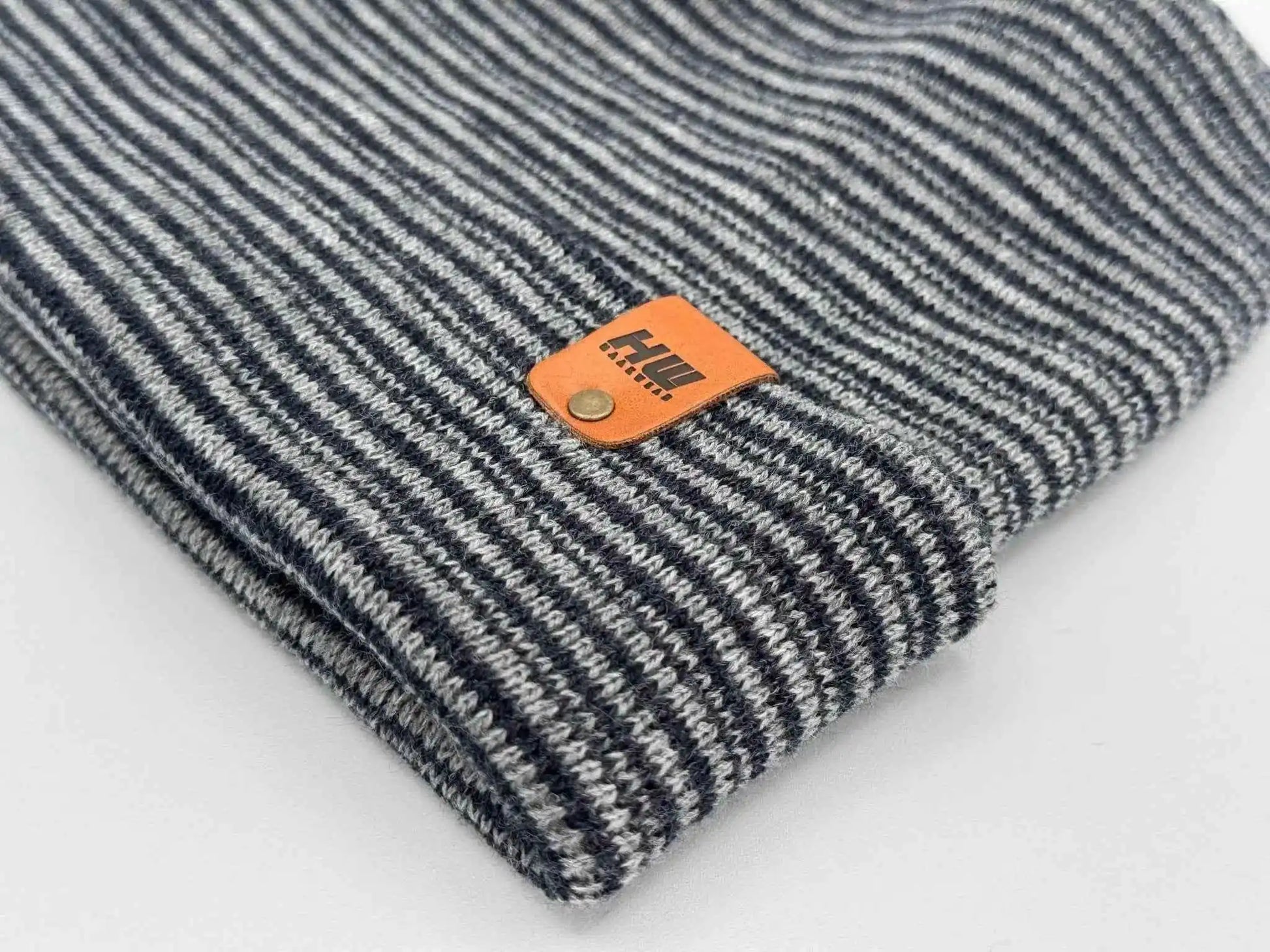 Striped cuffed beanie detail, gray and dark blue knit with orange logo patch