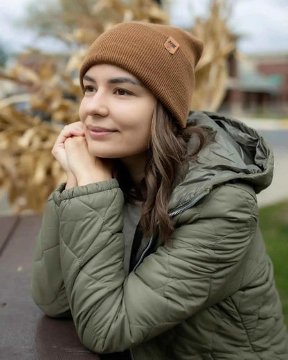 Camel brown knit beanie with folded cuff and logo patch, worn by person
