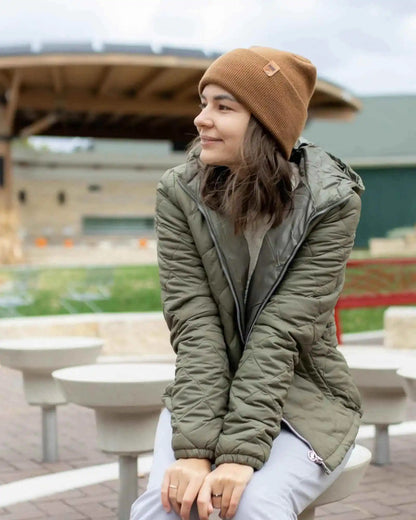 Camel brown beanie with folded brim and small logo patch, worn outdoors