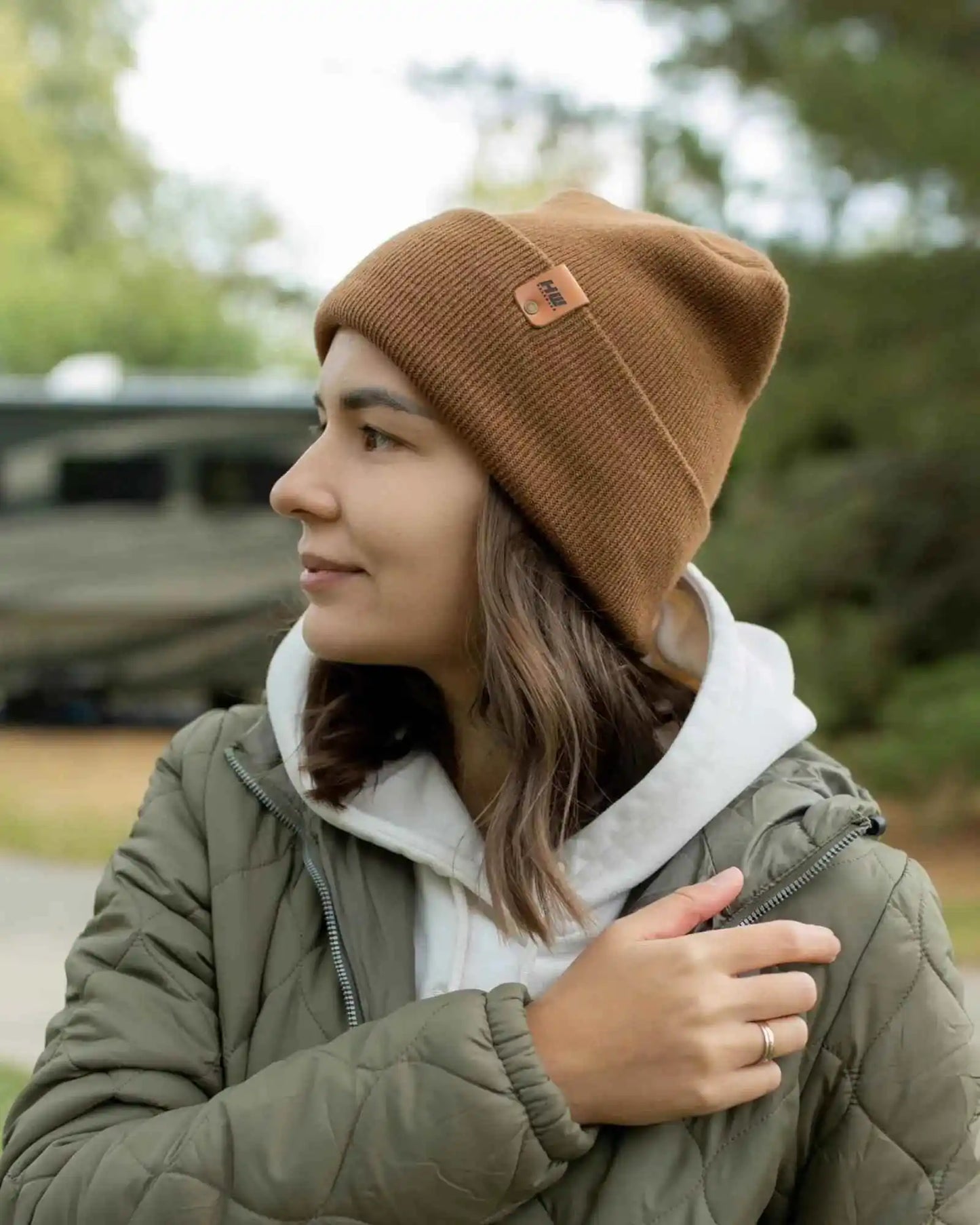 Camel brown cuffed beanie with logo patch, worn by person outdoors