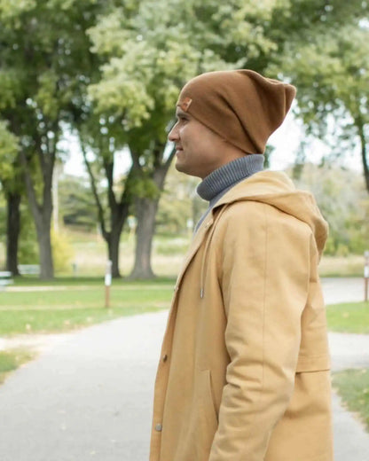 Camel brown ribbed beanie with turned cuff and small front tag, worn in profile