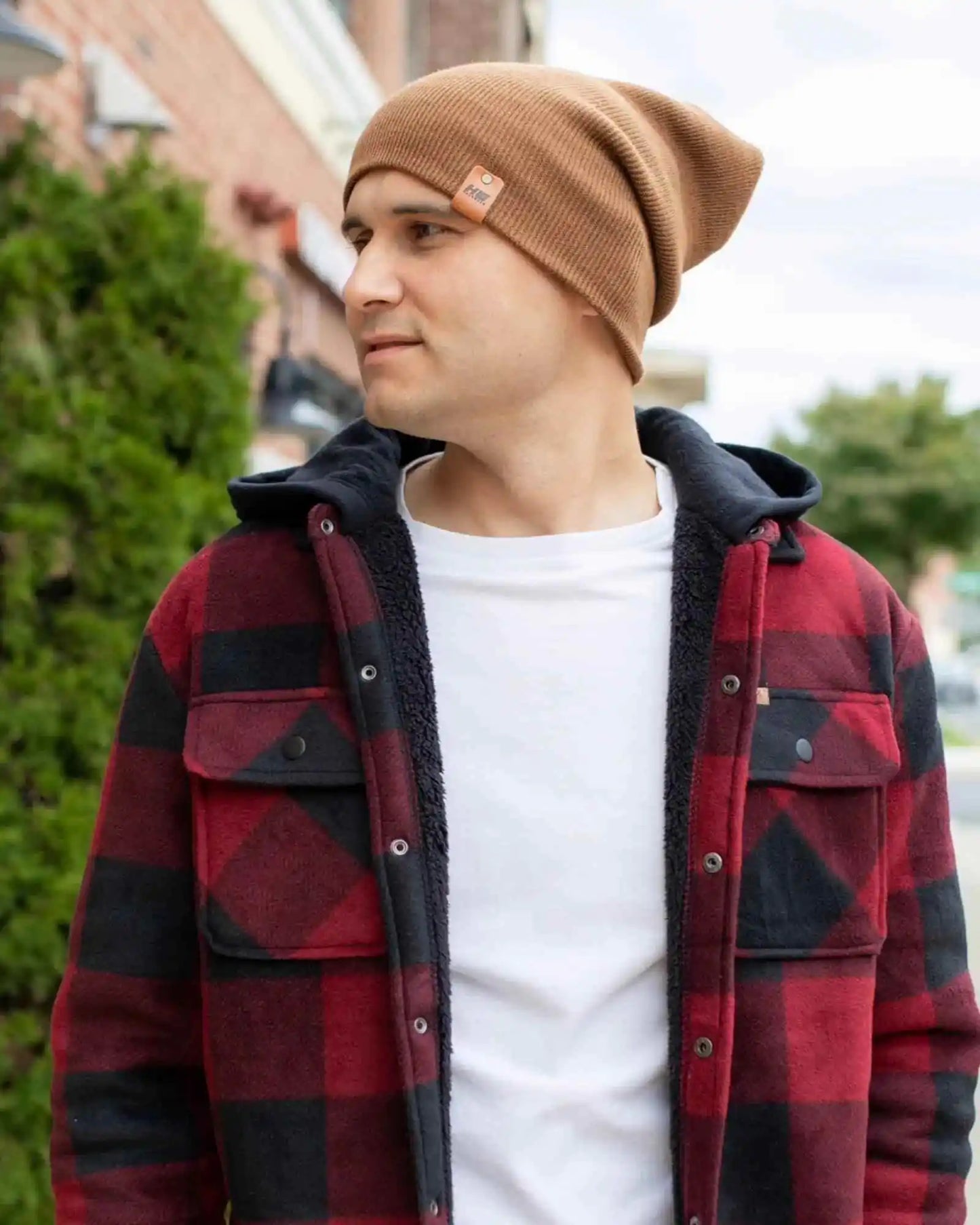 Camel brown cuffed beanie with small logo patch on front, worn with jacket